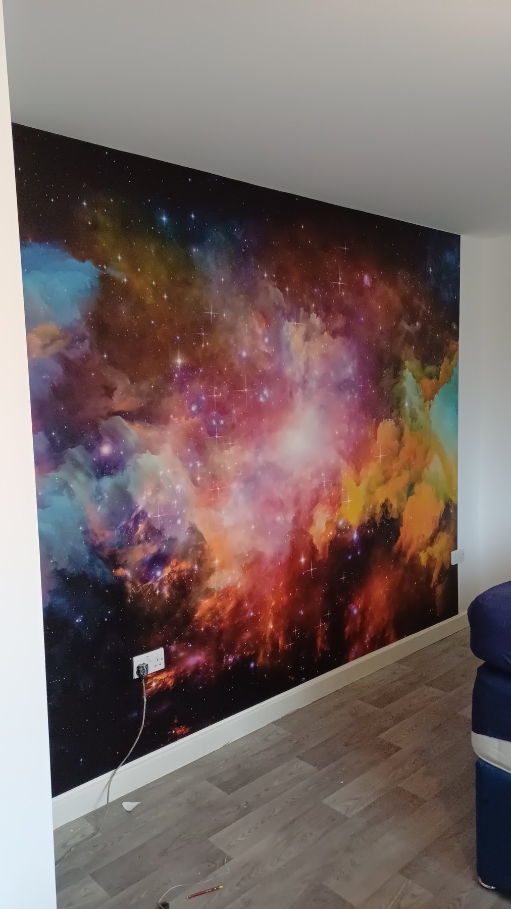 A feature wall papered floor to ceiling with a galaxy mural