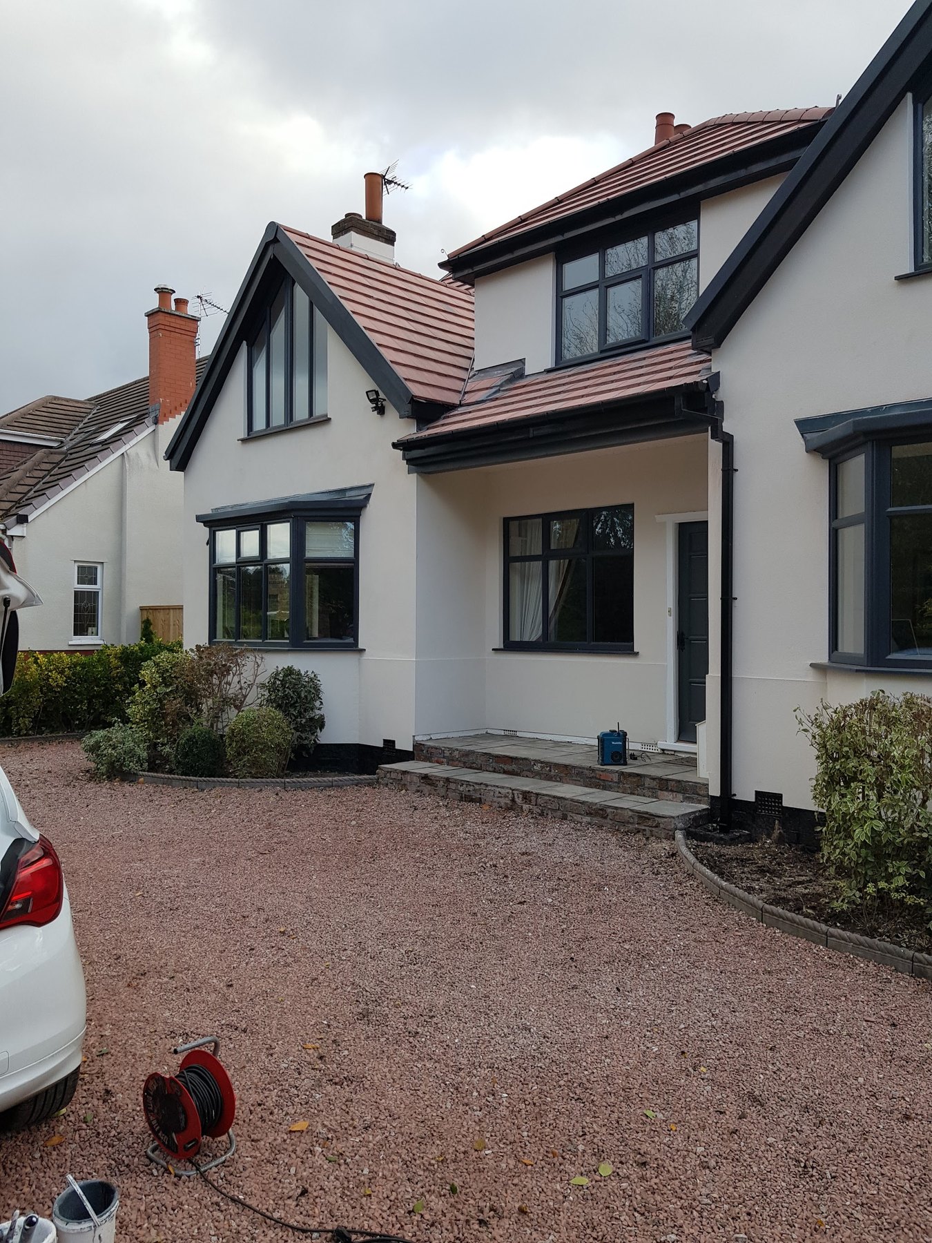 The outside of a detached house painted cream, with black windows, gutters and trim