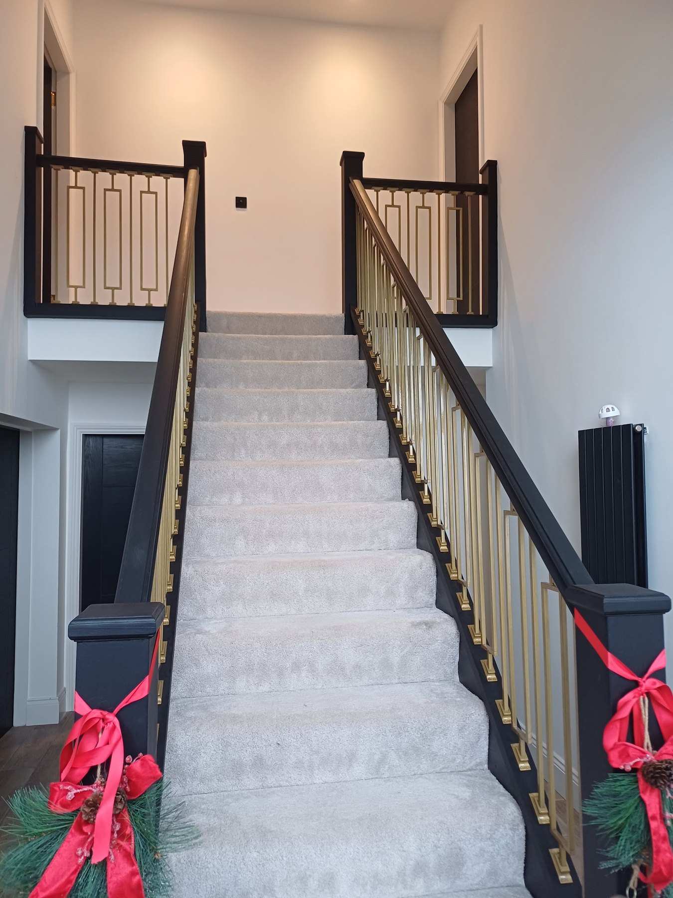 A staircase with black handrails and newel posts and gold spindles